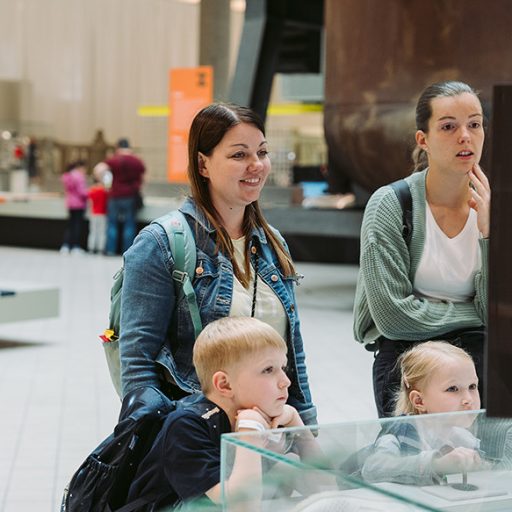Two women with two young children are viewing the exhibition at the voestalpine familiday. The children appear curious; one woman is smiling while the other looks thoughtful.