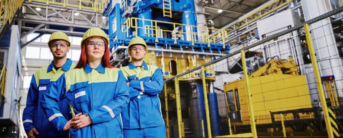 steel plant workers in safety gear smiling at the camera